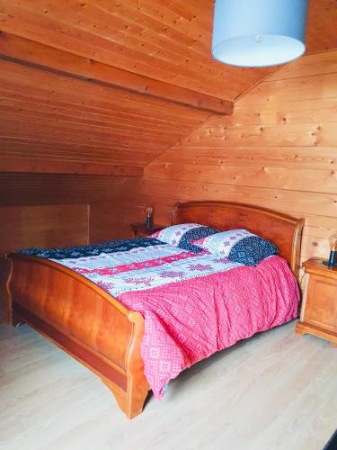 a bed in a room with a wooden ceiling at O'Doubs Chalet in La Chaux Neuve