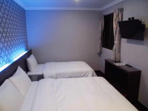 a hotel room with two beds and a television at 欣悅商務旅店 in Toufen