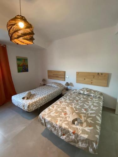 two beds in a small room with a light at Apartamento con vistas a la Playa con Ascensor y WIFI 9 pax in Daimuz