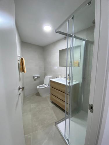 a bathroom with a toilet and a glass shower door at Apartamento con vistas a la Playa con Ascensor y WIFI 9 pax in Daimuz