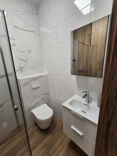 a white bathroom with a toilet and a sink at TRIO HoSteL in Hajnówka