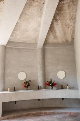 a room with two vases of flowers on a stone wall at Ahora Wellness Hostel in Guachaca