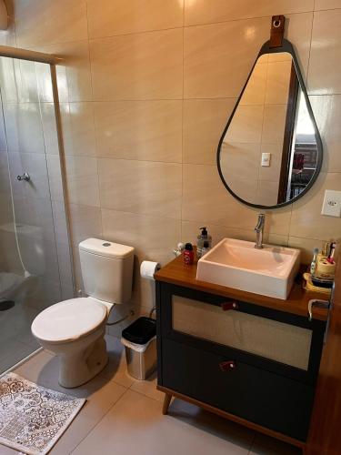 a bathroom with a toilet and a sink and a mirror at Recanto Miramonti Refúgio com Vista in Cristina