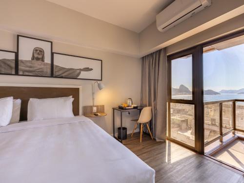 a bedroom with a bed and a large window at B&B HOTEL Rio Copacabana Posto 5 in Rio de Janeiro