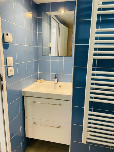 a blue tiled bathroom with a sink and a mirror at Le Clos - Proximité plage in Ambleteuse