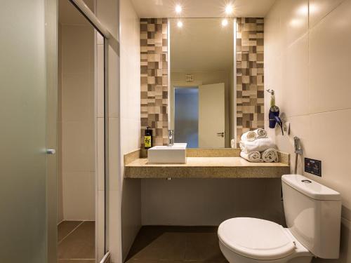 a bathroom with a toilet and a sink and a mirror at B&B HOTEL Rio Copacabana Posto 5 in Rio de Janeiro