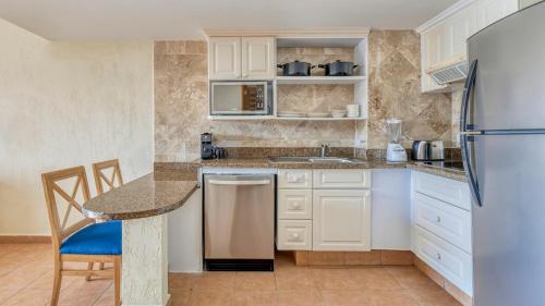a kitchen with white cabinets and a table and a refrigerator at Fiesta Americana Cancun Villas in Cancún