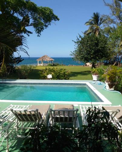 a swimming pool with chairs and the ocean in the background at The Rocks Villa in Tower Isle