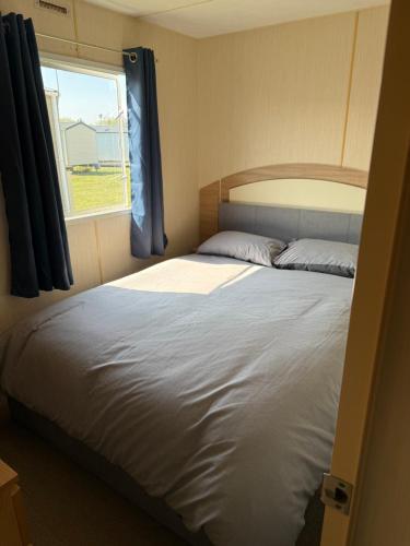 a bedroom with a large bed with a window at Holiday Caravan Orchards Holiday Village in Brightlingsea