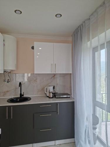 a kitchen with white cabinets and a sink and a window at Hyuratun Lori