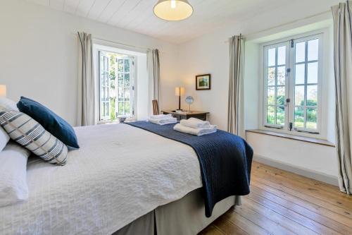 a bedroom with a large bed and two windows at 3 Bed in Lostwithiel oc-cwhite in Saint Winnow