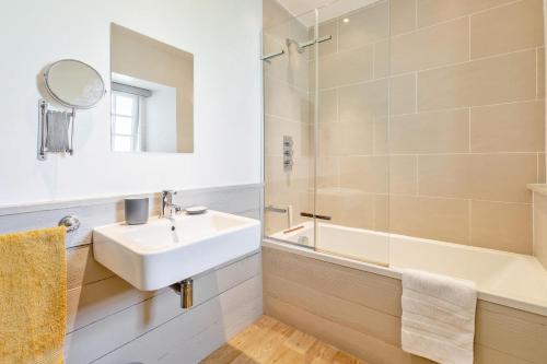 a bathroom with a sink and a tub and a mirror at 3 Bed in Lostwithiel oc-cwhite in Saint Winnow