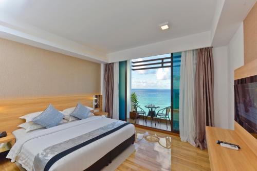 a bedroom with a bed and a view of the ocean at Arena Beach Hotel in Maafushi