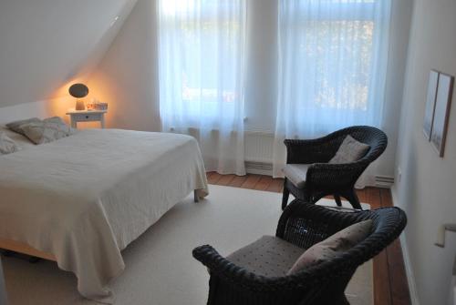 a bedroom with a bed and two chairs at Friesen-Cottage in Friedrichstadt