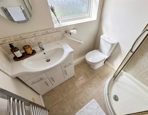a bathroom with a sink and a toilet and a mirror at Tharsh Peaceful Escape Double Room with Shared Bathroom in Coundon