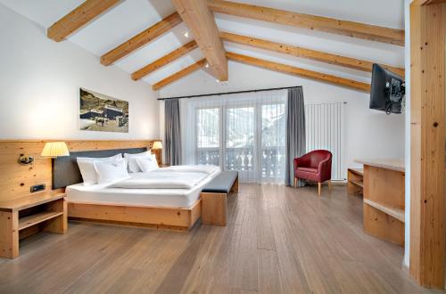 a bedroom with a bed and a red chair at Hotel Chalet Dlaces in Selva di Val Gardena