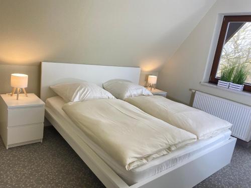 a bedroom with two beds with white sheets and a window at Finnhaus Fiete in Marlow