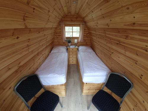 two beds in a wooden room with two chairs at 39 Mini Pod "Treene" in Silberstedt