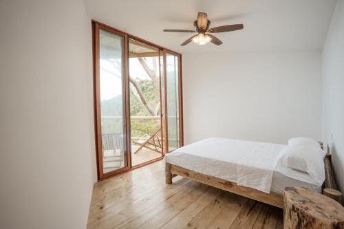 a bedroom with a bed and a ceiling fan at Ahora Wellness Hostel in Guachaca