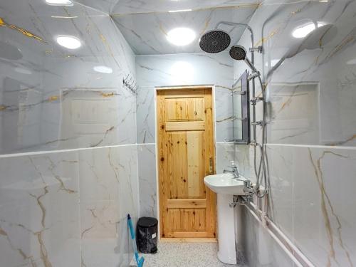 a bathroom with a sink and a wooden door at Xinaliq Khinalig İzzet's Riverside Home Stay in Xınalıq