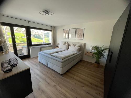 a bedroom with a white bed and a large window at Ferienwohnung Bächle in Bad Peterstal
