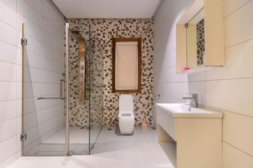 a bathroom with a shower and a toilet and a sink at Bridge Apartment Lagos in Lekki