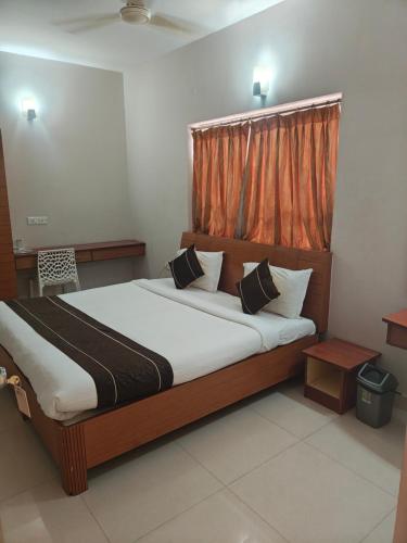 a bedroom with a large bed with an orange curtain at skylink residency in Chennai