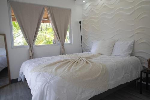 a bedroom with a white bed with two windows at La Ceiba Suite 2 with private plunge pool in Anasco
