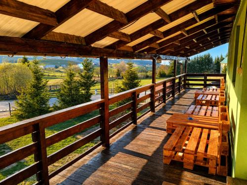 a deck with wooden benches and a view of a field at Pensiunea Alpin Marisel Self Check-in in Mărişel