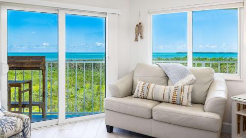 a living room with a couch and views of the ocean at Sunrise Oasis - Top Floor Ocean Pointe 2411 in Key Largo