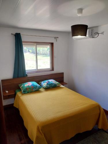 a bedroom with a yellow bed with a window at Le coin des Maripas in Quesnel