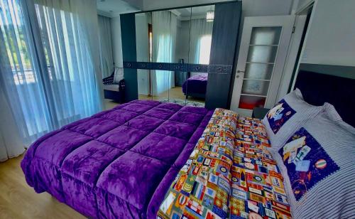 a bedroom with a purple comforter on a bed at Seafront Apartment Rize - Ardeşen in Ardeşen