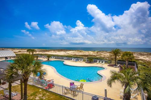 a resort swimming pool with palm trees and the ocean at Plantation East #3117 in Gulf Highlands