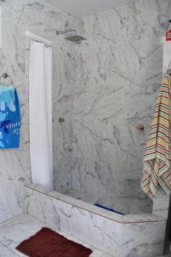 a bathroom with a shower with a white marble wall at Rincón de Rodríguez in General Rodríguez