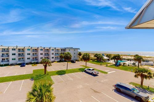 an apartment complex with a parking lot and palm trees at Hotel condo features beach access shared pool - near town in Fort Morgan