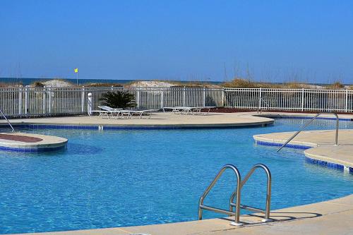 a swimming pool with blue water and a fence at Contemporary beachside escape with gym & pools in Fort Morgan