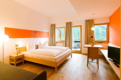 a hotel room with a bed and a television at Hotel Schweigl in Ultimo
