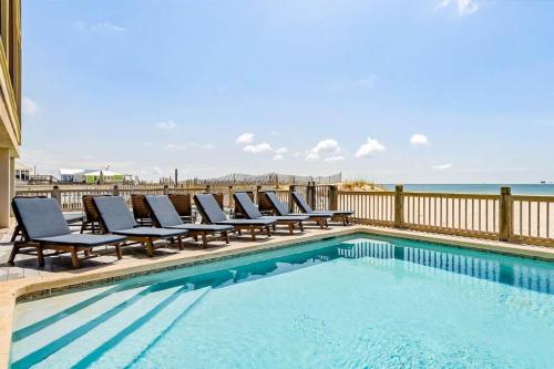 a pool with chairs and the ocean in the background at Beachfront dog-friendly home with private pool sundeck and elevator in Fort Morgan