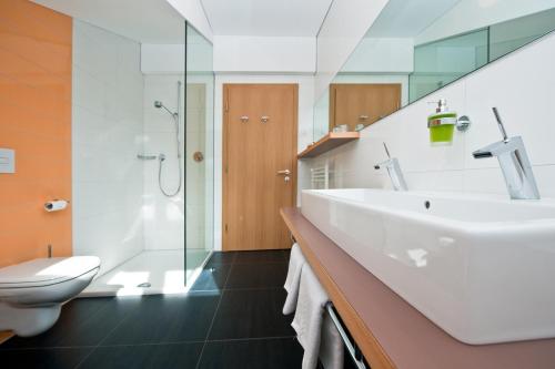 a bathroom with a white sink and a toilet at Hotel Schweigl in Ultimo