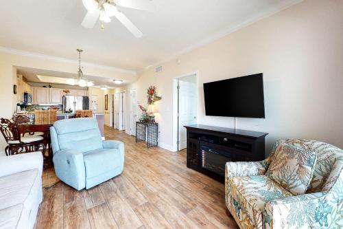 a living room with a television and a couch and chairs at Crystal Tower 705 in Gulf Shores
