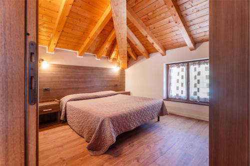 a bedroom with a bed and a wooden ceiling at CROSINA HOLIDAY - Casa Al Ponte in Ledro