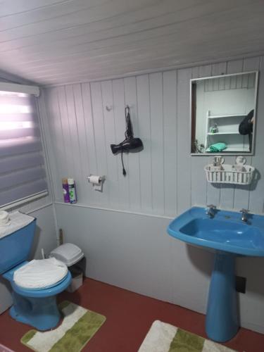 a bathroom with a blue toilet and a sink at Cabañas casa blanca in Laraquete