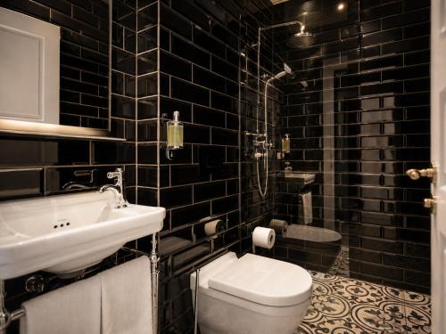 a black tiled bathroom with a toilet and a sink at ASKA Holt in Reykjavík