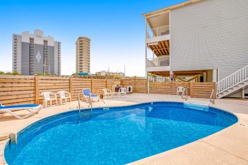 a swimming pool with chairs and a building at Sun & Sea in Gulf Shores