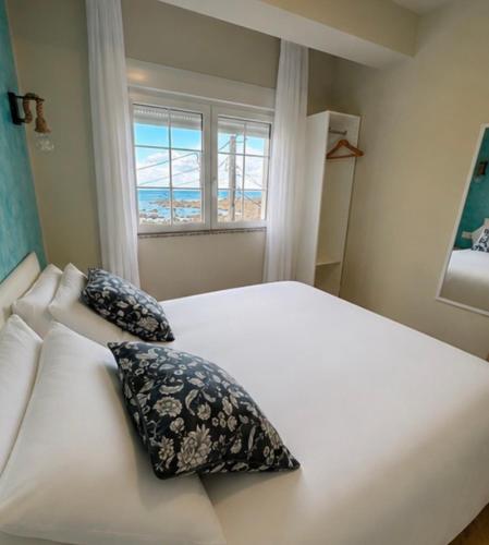 a bedroom with a bed with two pillows and a window at Muxia Mare in Muxia