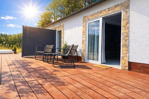 a deck with chairs and a sliding glass door at Mazury Apartamenty wodne tarasy Blue - Ruś in Ruś