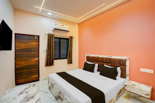 a bedroom with a bed with an orange wall at Hotel O DELIGHT INN in Chandrapur