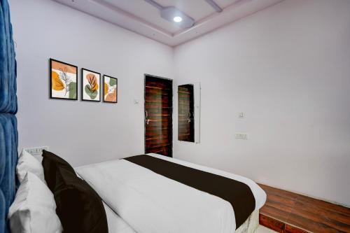 a bedroom with a white bed with three pictures on the wall at Hotel O DELIGHT INN in Chandrapur
