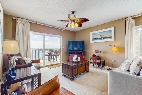 a living room with a couch and a tv at Beachfront condo with shared pool outdoor shower and beach access in Gulf Shores