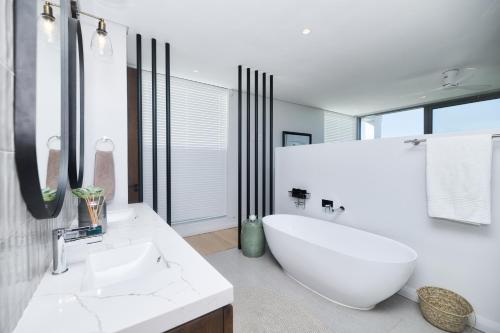 a bathroom with a large white tub and a sink at Sonvanger Villa Struisbaai in Struisbaai